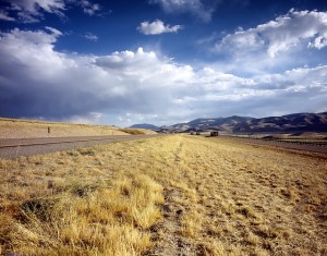 Open landscape in Idaho with dry grass, distant mountains, and a cloudy sky, reflecting the potential for land ownership and development in real estate transactions.