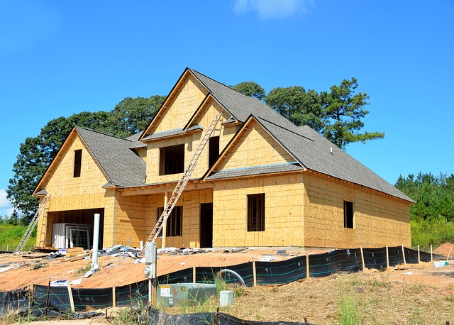 Newly constructed house with wooden framing, ladder propped against the side, surrounded by construction materials, illustrating the process of building a home for FHA construction loan options.
